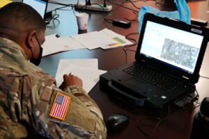 A soldier sitting at a table with a laptop.