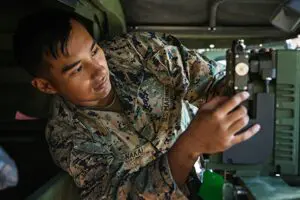 A marine is working on a computer in a military vehicle.
