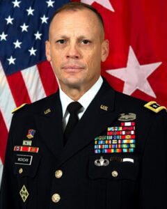 A man in a military uniform standing in front of an american flag.