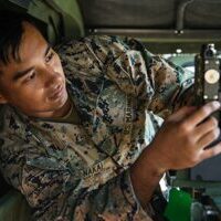A marine is working on a computer in a military vehicle.